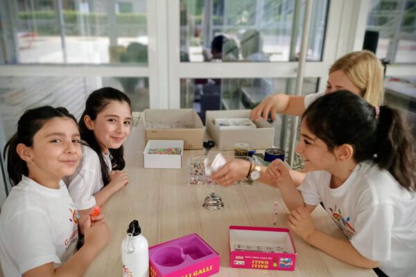Mädchen und eine Frau spielen "Halli Galli" an einem Tisch voller Bastelmaterialien.